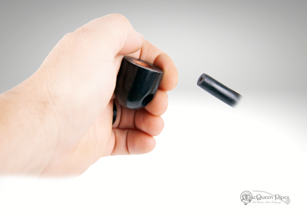 A hand-carved miniature traveler pipe, crafted from briar wood, resting on a textured surface.